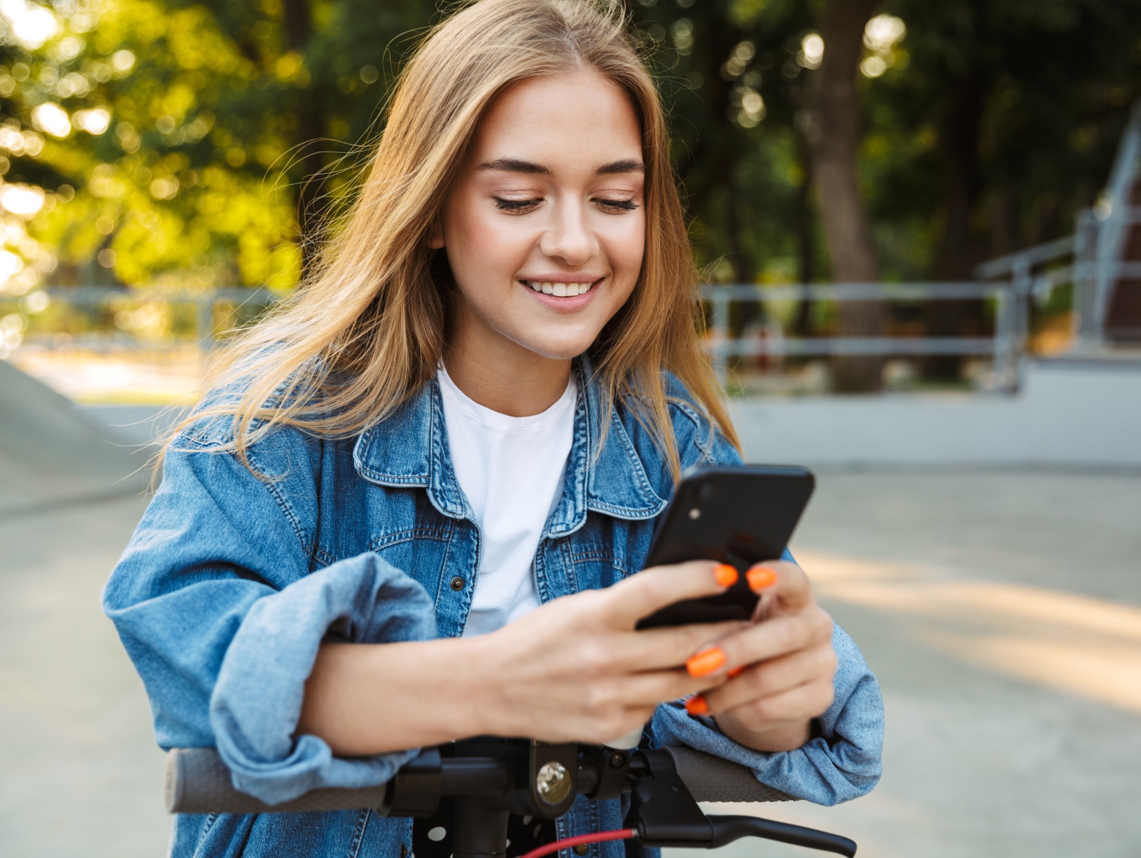 Jungendliche auf Scooter mit Smartphone
